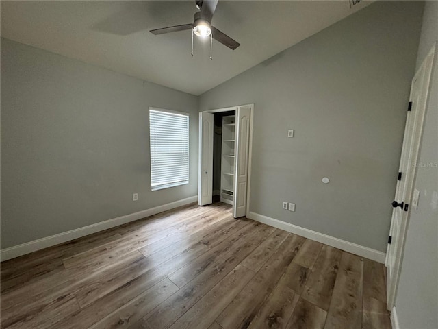 unfurnished bedroom featuring hardwood / wood-style floors, a closet, ceiling fan, and lofted ceiling