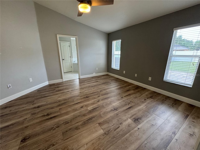 unfurnished bedroom with vaulted ceiling, hardwood / wood-style flooring, and multiple windows