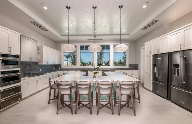 kitchen with a tray ceiling, sink, and hanging light fixtures