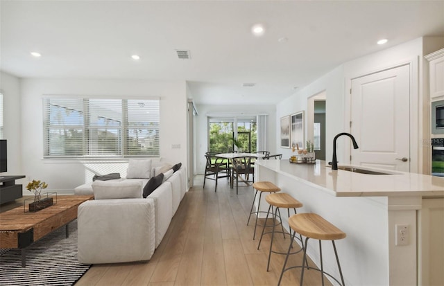 living room featuring sink and light hardwood / wood-style floors