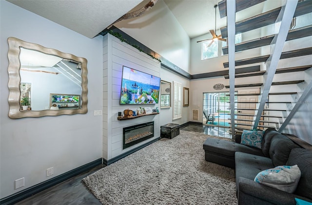 living room with ceiling fan, plenty of natural light, dark hardwood / wood-style floors, and a high ceiling