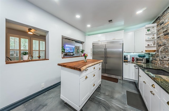 kitchen with white cabinetry, stainless steel appliances, sink, and butcher block countertops