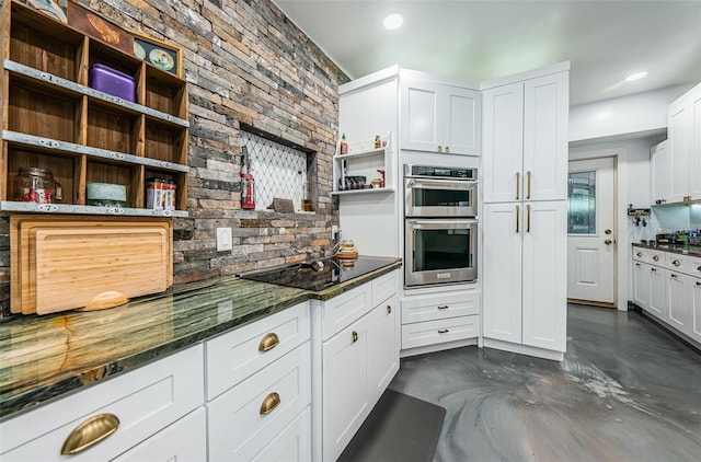 kitchen with white cabinetry, black electric stovetop, double oven, and dark stone counters