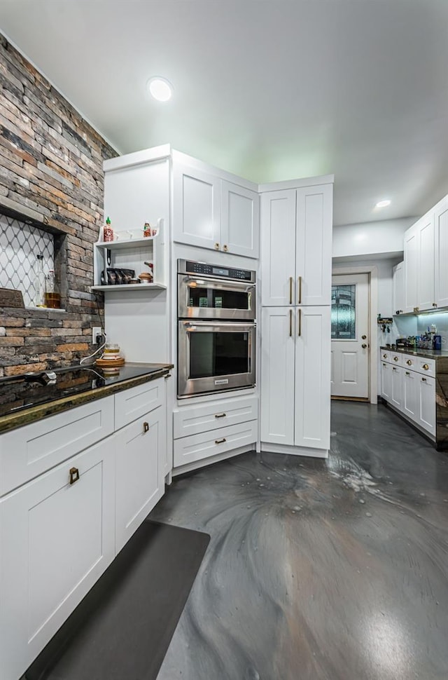 kitchen featuring dark stone countertops, double oven, and white cabinets