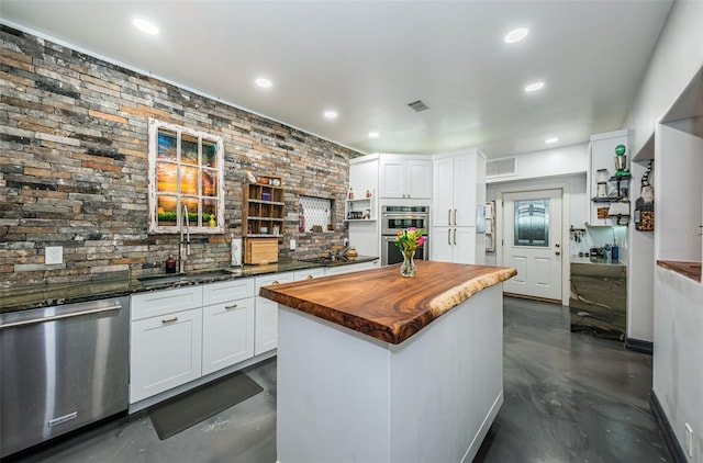 kitchen featuring a kitchen island, appliances with stainless steel finishes, wood counters, sink, and white cabinets