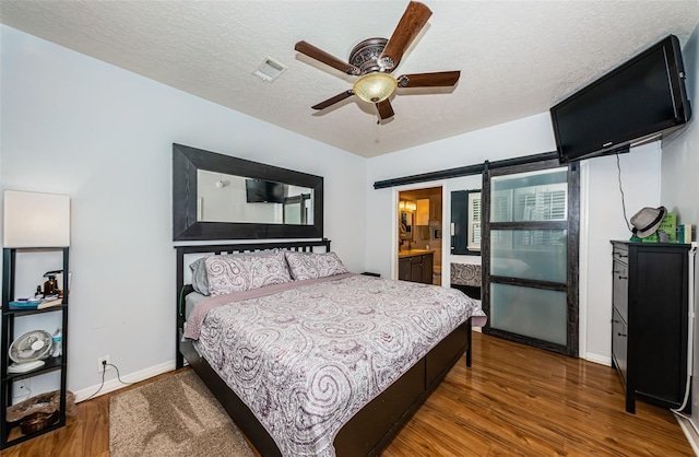 bedroom with dark hardwood / wood-style floors, a barn door, and a textured ceiling