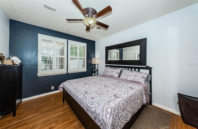 bedroom featuring ceiling fan, wood-type flooring, and a textured ceiling