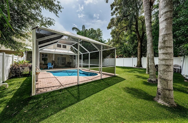 view of pool with a yard, a patio area, and glass enclosure