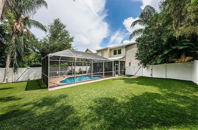 back of property with a fenced in pool and a lawn