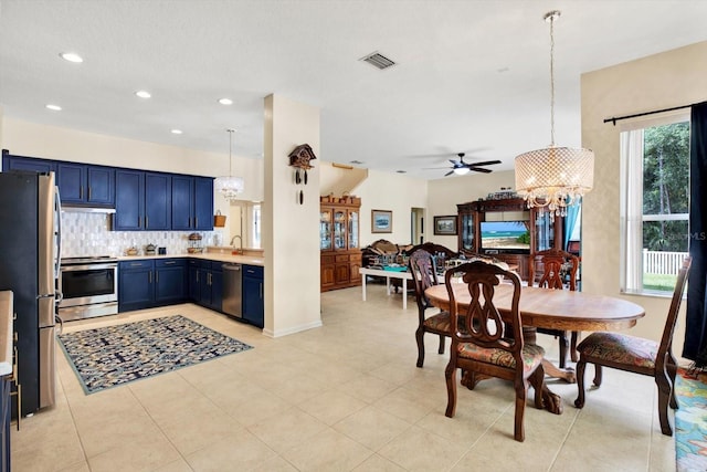 kitchen featuring ceiling fan with notable chandelier, blue cabinetry, appliances with stainless steel finishes, hanging light fixtures, and a healthy amount of sunlight