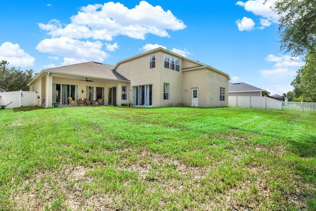 rear view of property featuring ceiling fan and a yard