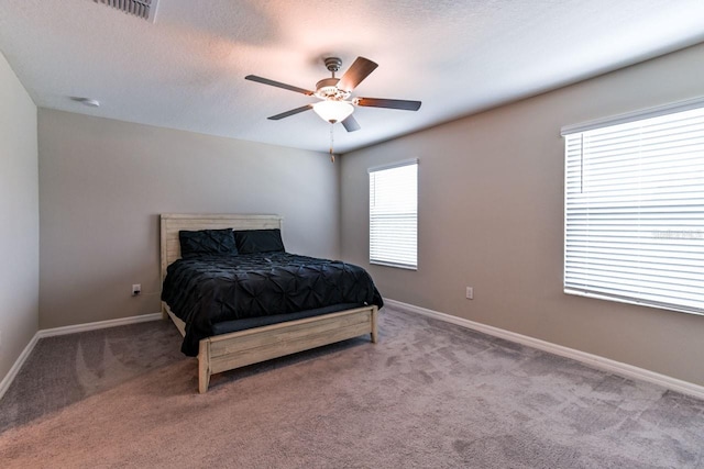 carpeted bedroom with ceiling fan and a textured ceiling