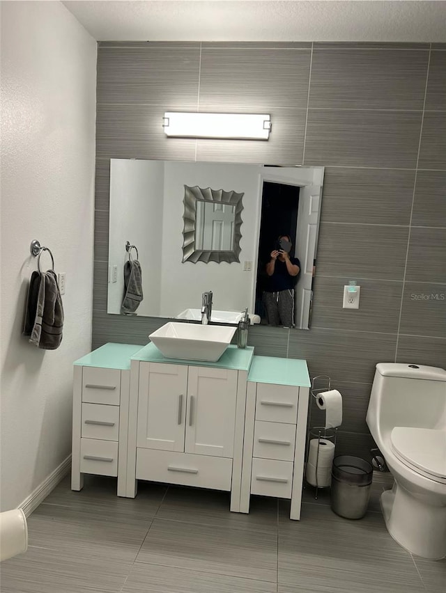 bathroom with vanity, tile walls, tile patterned floors, and toilet