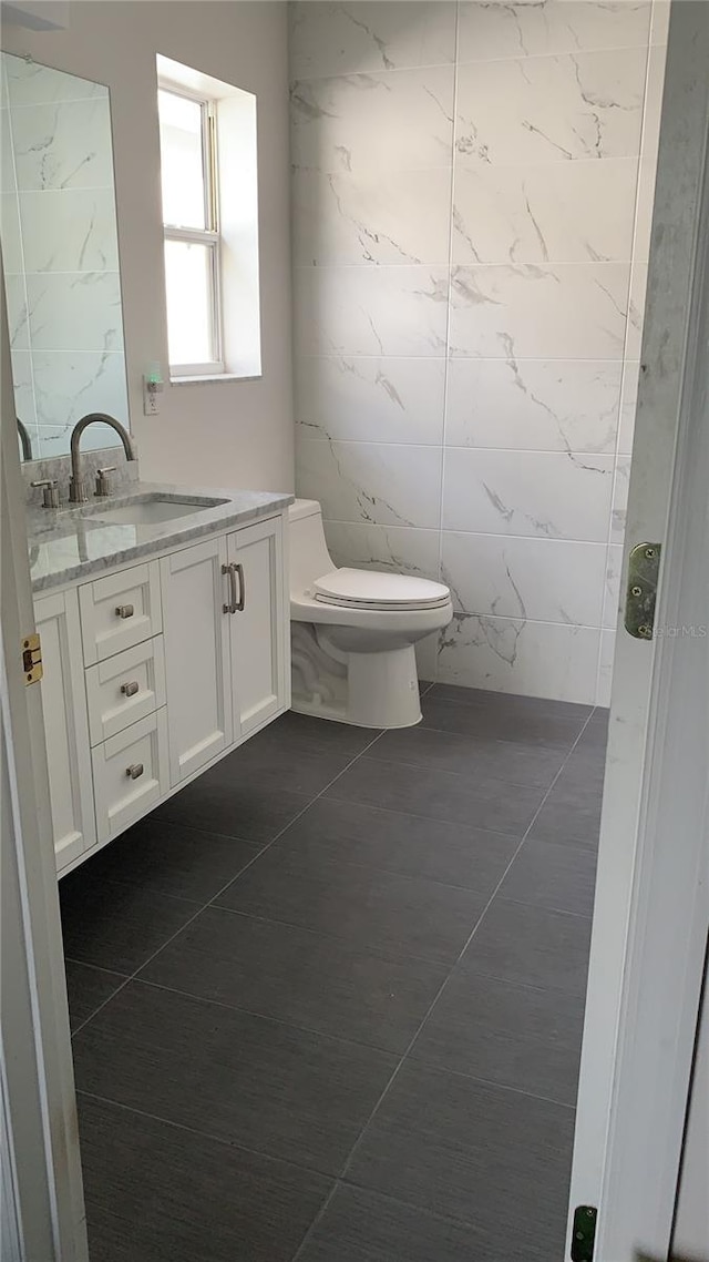 bathroom featuring vanity, toilet, tile patterned flooring, and tile walls