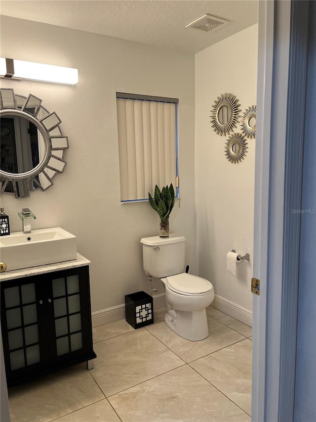 bathroom featuring tile patterned floors, vanity, toilet, and a textured ceiling