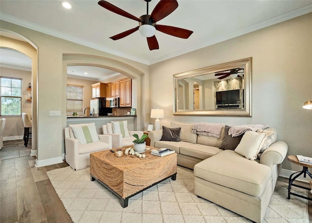 living room featuring light wood-type flooring, ceiling fan, and crown molding