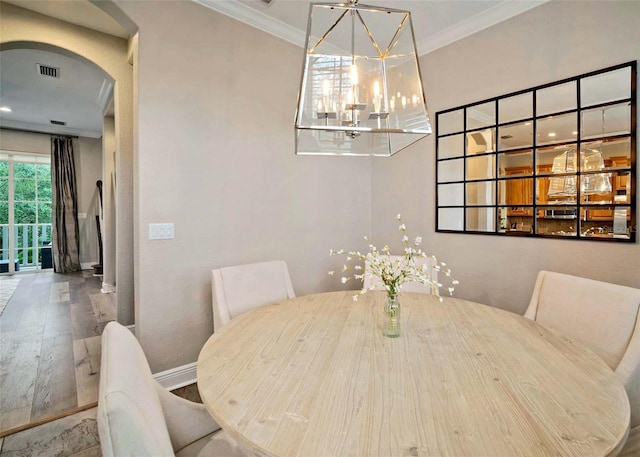 dining room featuring an inviting chandelier, hardwood / wood-style flooring, and crown molding