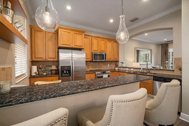 kitchen with kitchen peninsula, pendant lighting, a breakfast bar, appliances with stainless steel finishes, and sink