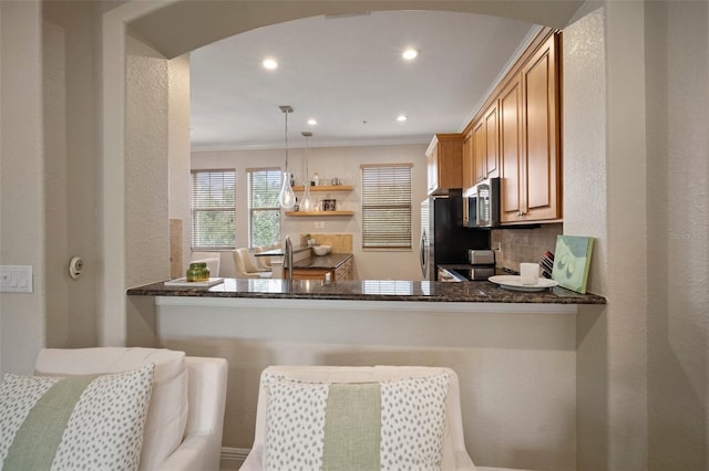 kitchen featuring hanging light fixtures, stainless steel appliances, kitchen peninsula, ornamental molding, and tasteful backsplash