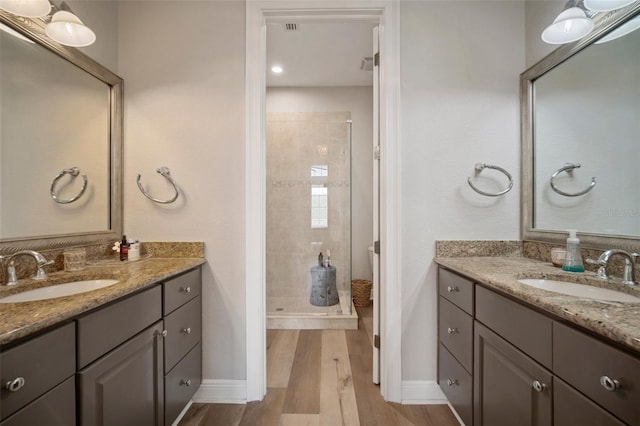 bathroom featuring a tile shower, wood-type flooring, and vanity