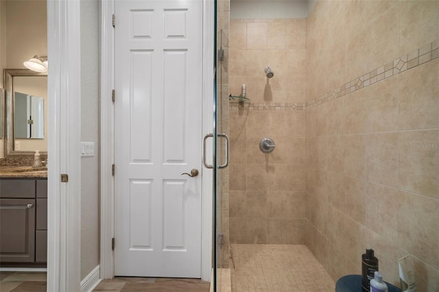 bathroom featuring a shower with door and vanity