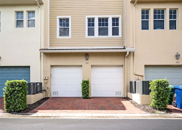 view of front of home with a garage and central air condition unit