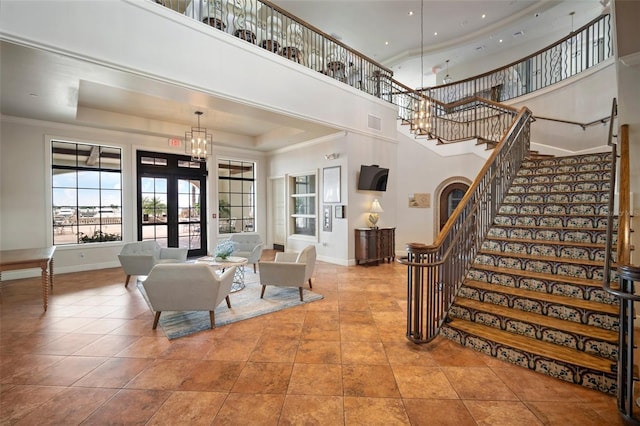 tiled living room featuring a towering ceiling, a raised ceiling, and french doors