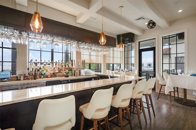 bar with decorative light fixtures, light stone countertops, beamed ceiling, and dark hardwood / wood-style floors