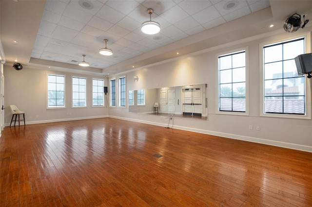 unfurnished living room featuring hardwood / wood-style floors, a raised ceiling, and a drop ceiling