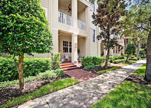 view of exterior entry featuring a balcony and ceiling fan