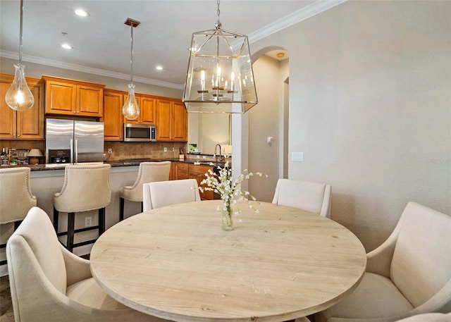 dining room featuring ornamental molding, a chandelier, and sink