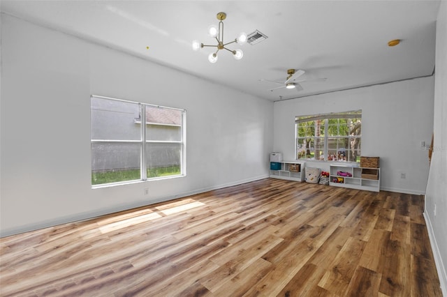 interior space featuring wood-type flooring, ceiling fan with notable chandelier, and plenty of natural light