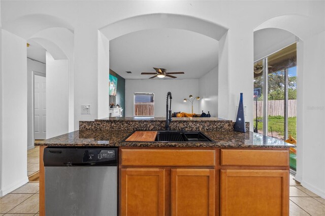 kitchen with dark stone countertops, dishwasher, ceiling fan, and light tile patterned floors