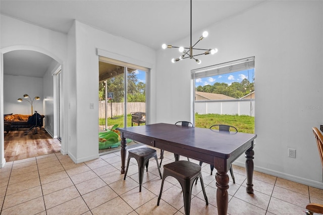 dining room featuring an inviting chandelier, light hardwood / wood-style flooring, and lofted ceiling