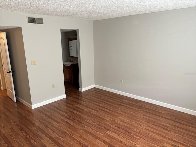 spare room featuring a textured ceiling, sink, and dark hardwood / wood-style floors