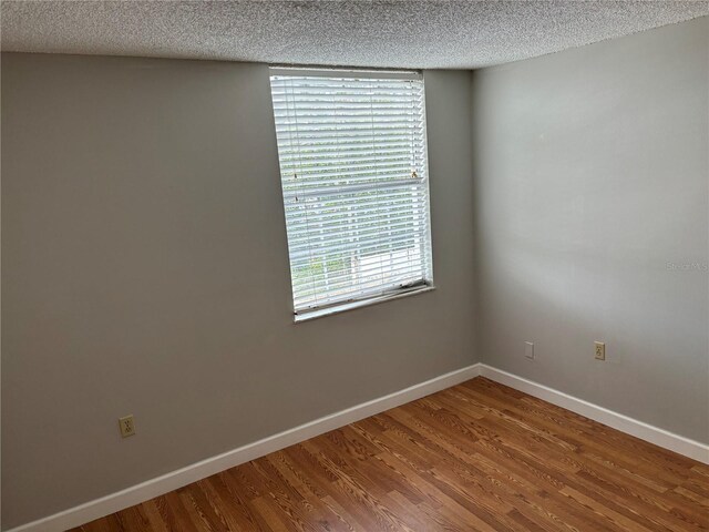 empty room featuring a textured ceiling and hardwood / wood-style flooring