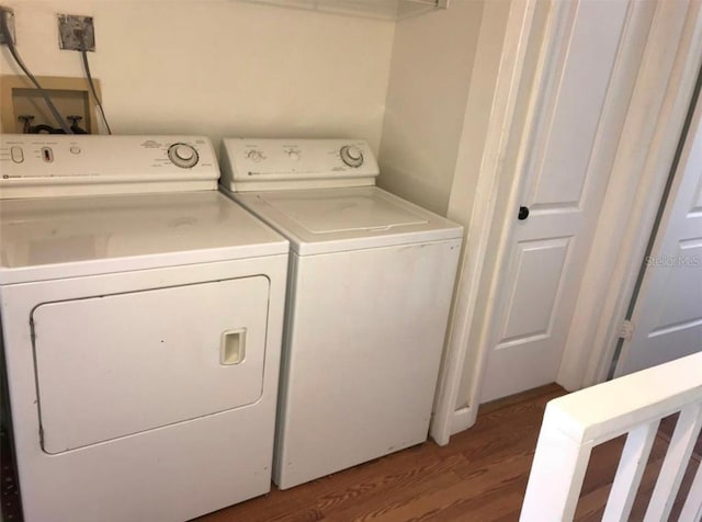 clothes washing area featuring washer and clothes dryer and wood-type flooring