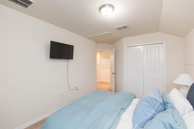 carpeted bedroom with vaulted ceiling, a closet, and a textured ceiling