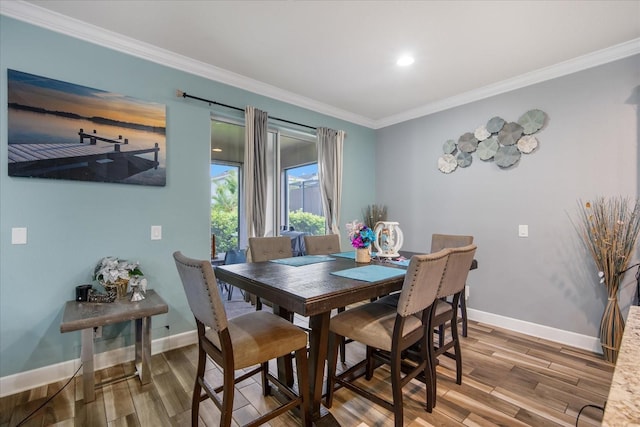 dining room with ornamental molding and hardwood / wood-style flooring