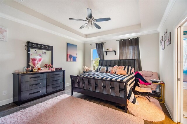 bedroom featuring wood-type flooring, a raised ceiling, crown molding, and ceiling fan