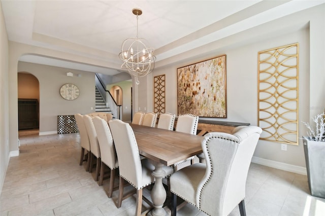 dining area featuring a raised ceiling, a chandelier, and light tile patterned floors