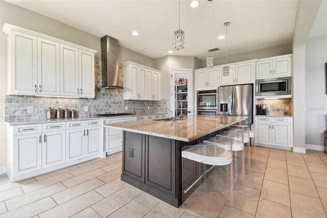 kitchen with tasteful backsplash, white cabinets, wall chimney range hood, and stainless steel appliances