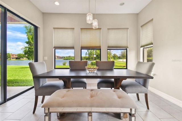 dining area with a water view and light tile patterned floors