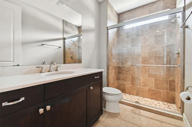 bathroom featuring toilet, an enclosed shower, vanity, and tile patterned flooring