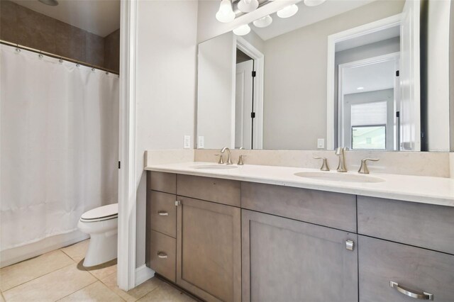 bathroom with dual vanity, toilet, and tile patterned floors