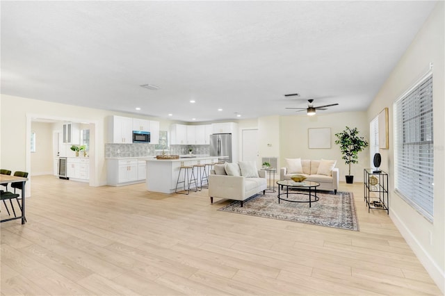 living room with ceiling fan and light hardwood / wood-style floors