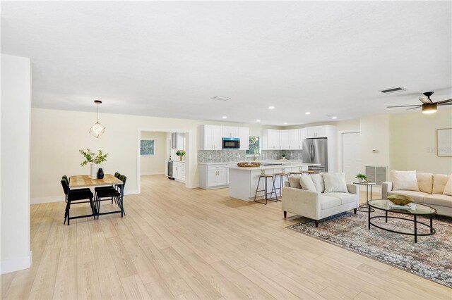 living room with ceiling fan and light hardwood / wood-style flooring