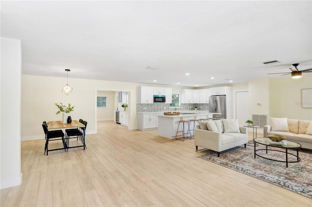 living area with light wood-style floors, visible vents, and recessed lighting