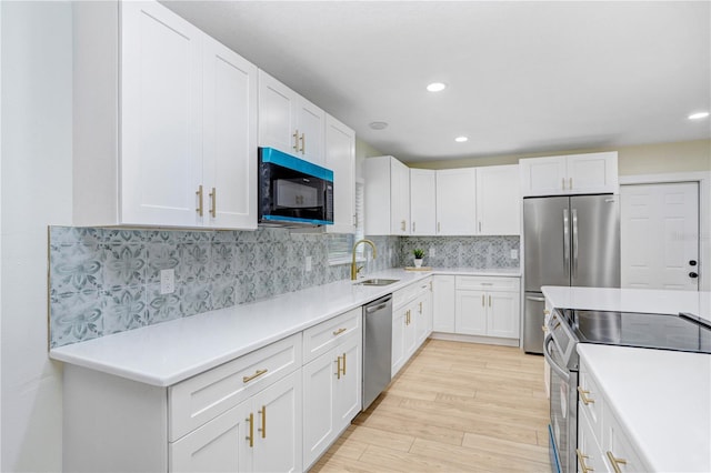 kitchen featuring tasteful backsplash, light wood-type flooring, stainless steel appliances, and white cabinets