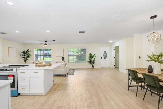 kitchen featuring white cabinets, light wood-type flooring, ceiling fan, and decorative light fixtures